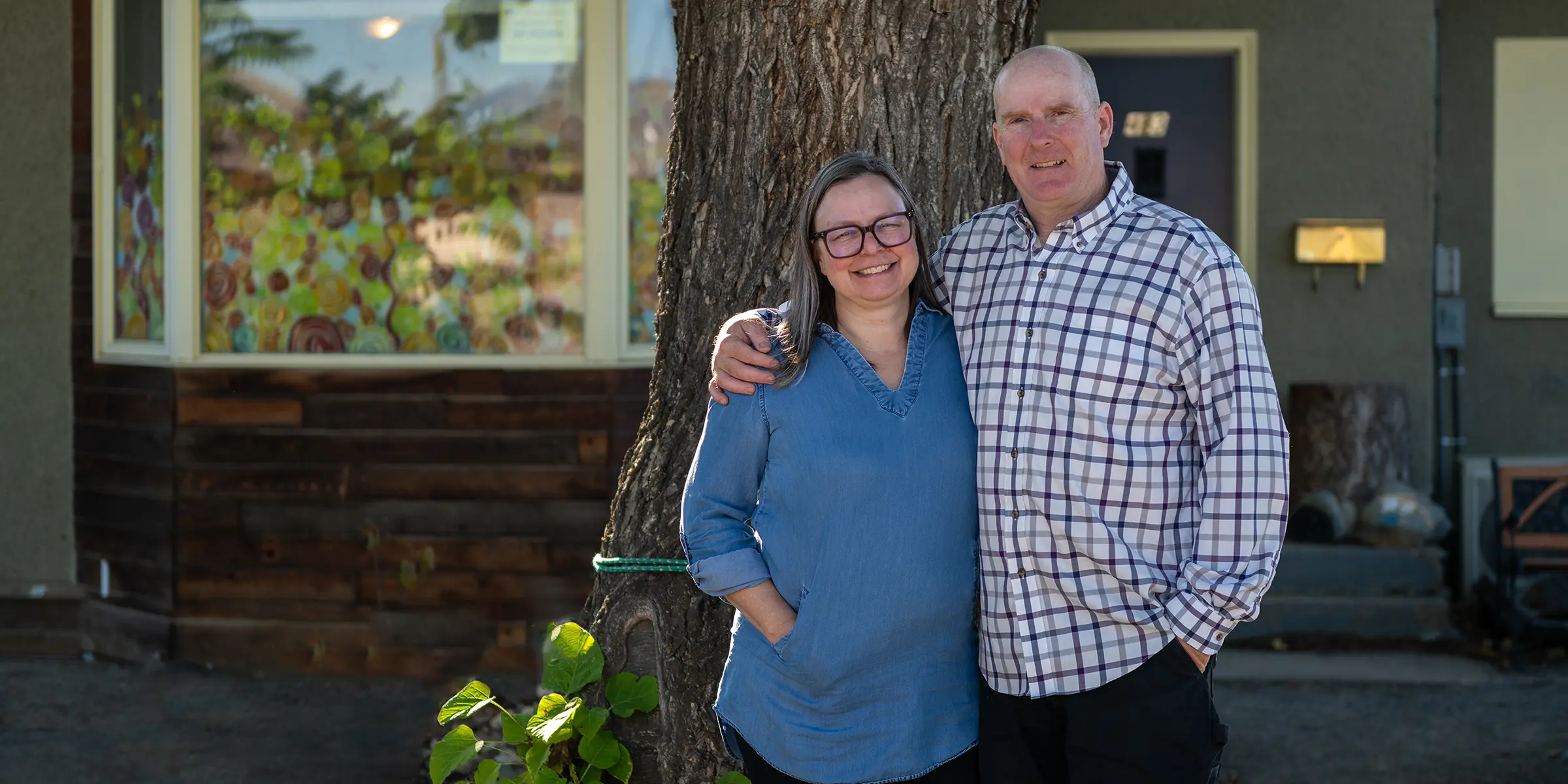 Woman and man, arm and arm, in front of retrofitted home.
