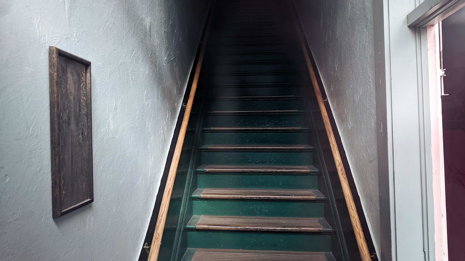 Staircase with painted green risers and wood treads disappears into darkness.