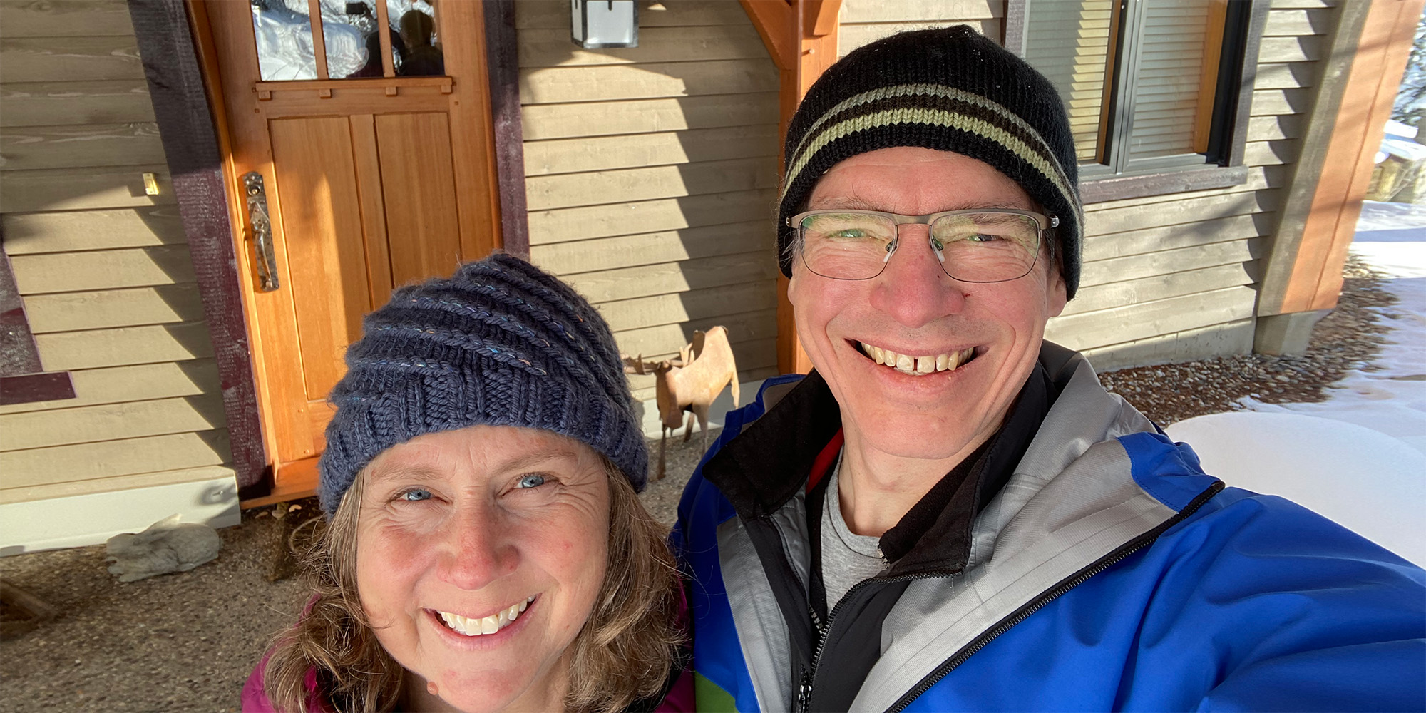 Woman and man in winter gear smile up at the camera.