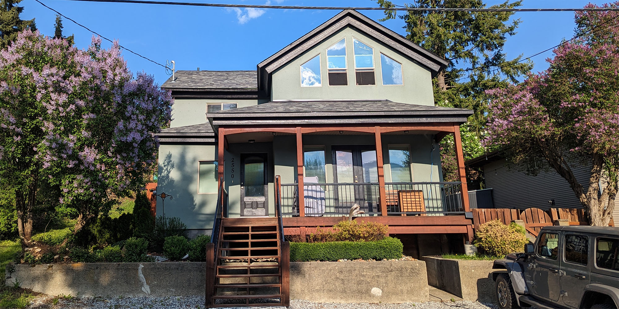 Old style two storey home with wood trimmed porch and steps leading toward viewer.