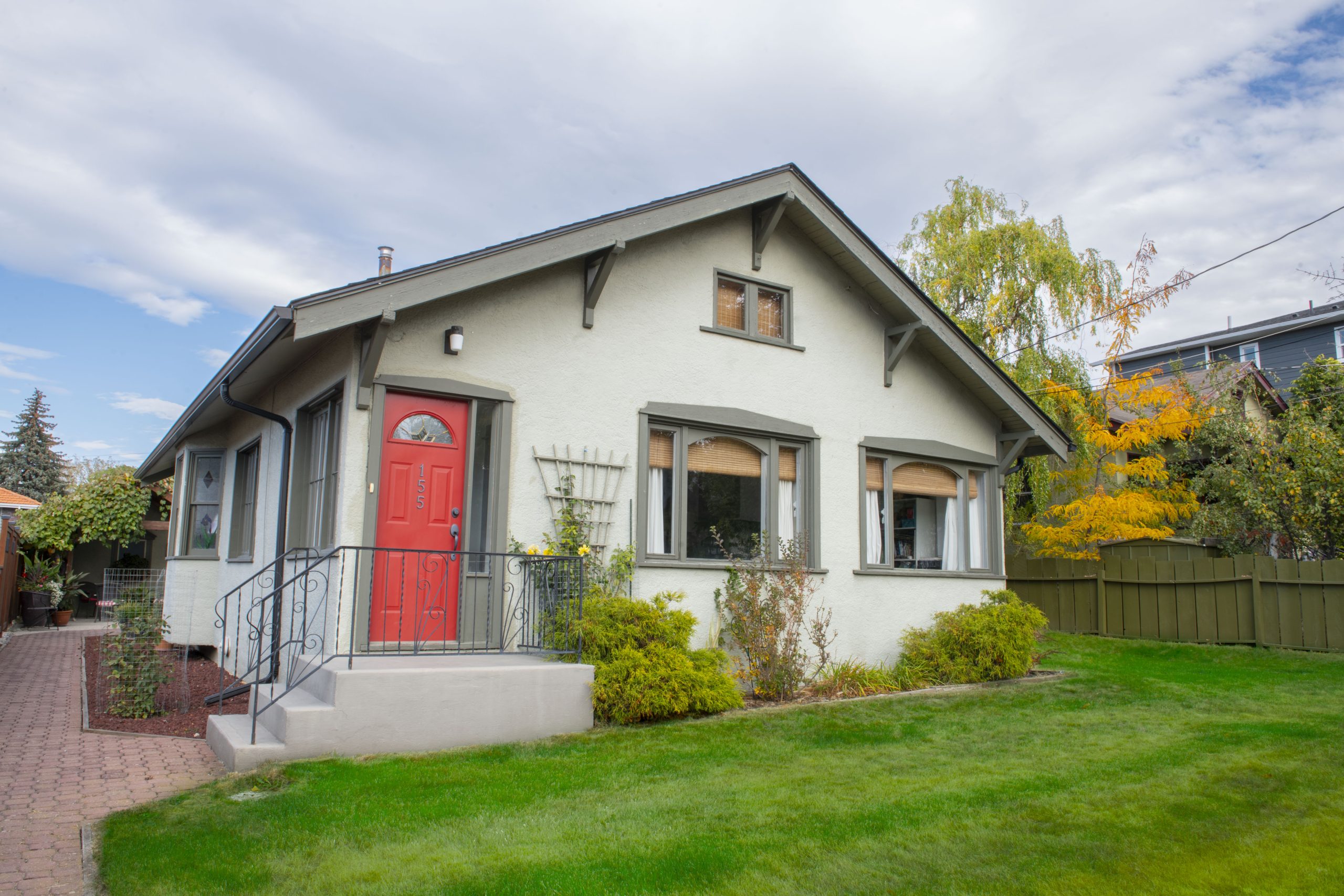 Bungalow with red door and green front lawn.